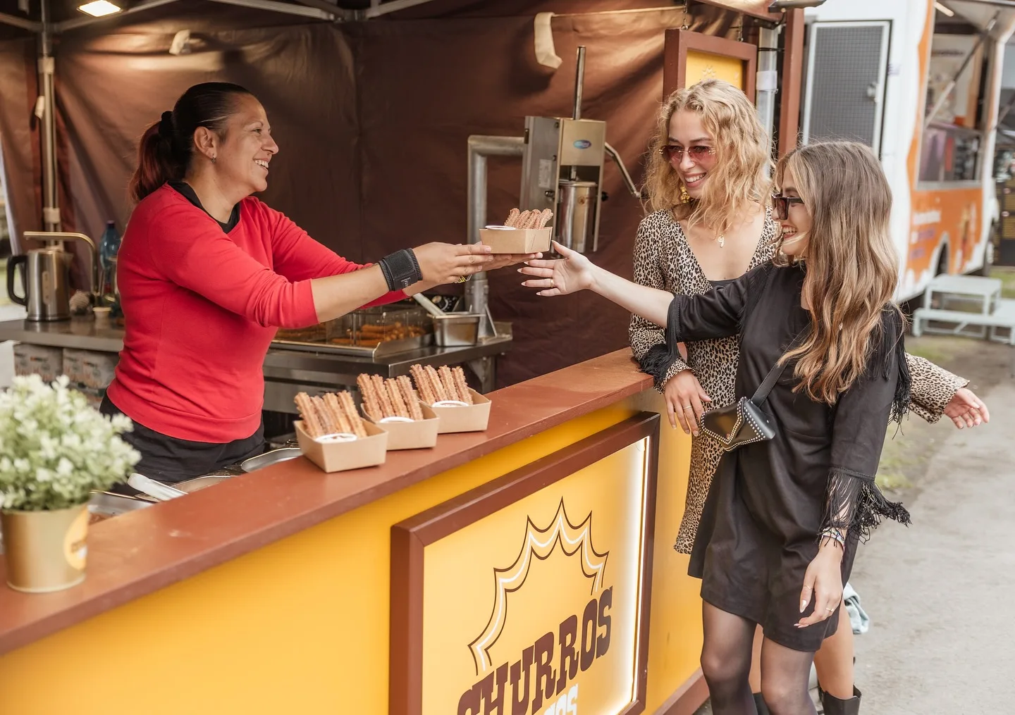 Obsluha Churros Chocos předává churros dvěma zákaznicím